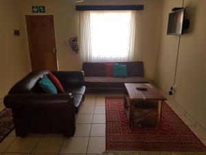 ein Wohnzimmer mit einem Sofa und einem Couchtisch in der Unterkunft Emerald Bed&Breakfast in Windhoek
