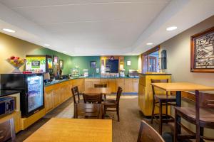 a restaurant with wooden tables and chairs and a kitchen at AmericInn by Wyndham Kearney in Kearney