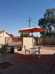 einen Tisch, zwei Stühle und einen Regenschirm in der Unterkunft Emerald Bed&Breakfast in Windhoek
