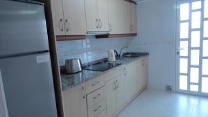 シウダー・ケサダにあるHE Huelva - Quesadaの白いキャビネット、シンク、冷蔵庫付きのキッチンが備わります。