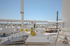 una mesa con un libro y copas de vino en el balcón en Naxos Dream Oniro Studios - Adults Only, en Naxos Chora