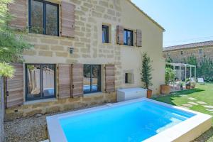 una casa con piscina frente a una casa en La maison du Boulodrome, en La Bruguière