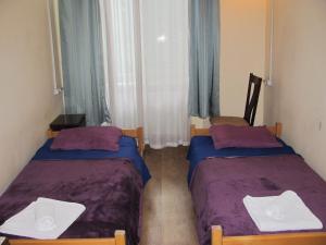 two beds in a small room with blue curtains at Lucky Travelers Room in Tbilisi City