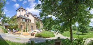 a large stone house with a tree in front of it at Ecrin du Ségala - Chambres d'hôtes in Tauriac-de-Naucelle