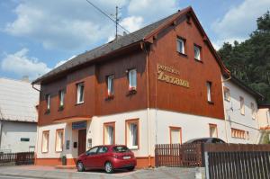 a red car parked in front of a building at Penzion Zuzana in Staré Splavy