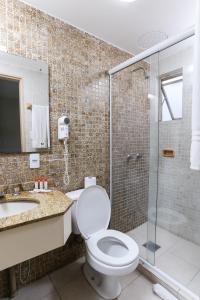 a bathroom with a toilet and a glass shower at Hotel Suárez Executive Novo Hamburgo in Novo Hamburgo