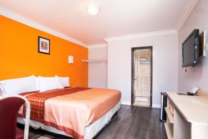 a hotel room with a bed with an orange wall at Value Inn Hollywood in Los Angeles