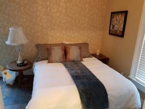 a bed in a bedroom with a lamp on a table at Hellemsfield Inn & bed and breakfast in Kingsville