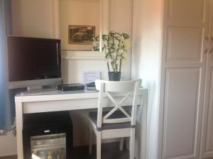 a white desk with a computer monitor and a chair at Albergo Rossella in Castiglione della Pescaia