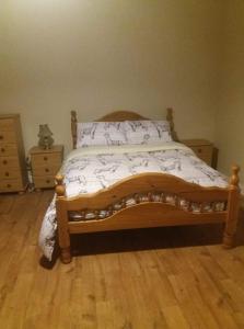 a bedroom with a wooden bed with a wooden floor at Castletownmoor Clinic & Permaculture Farm in Kells