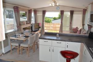 a kitchen with a table with chairs and a tv at The Balmoral Caravan in Dornoch