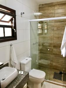uma casa de banho com um chuveiro, um WC e um lavatório. em Pousada Icaraí em Ilha Comprida