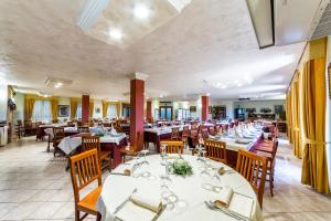 una sala da pranzo con tavoli bianchi e sedie in legno di Hotel Il Melograno a Tempio Pausania