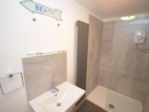 a bathroom with a white sink and a shower at Beach hut seaside cottage in Sheringham