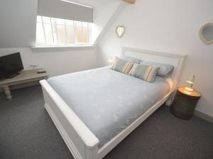 a white bedroom with a bed and a desk at Beach hut seaside cottage in Sheringham