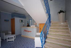 una escalera en un edificio con una mujer sentada en un mostrador en Hotel Il Melograno, en San Vito lo Capo