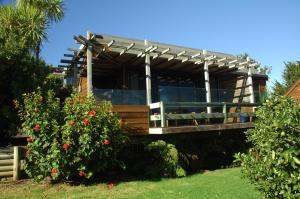 a wooden house with a pergola in a yard at Te Manaaki Villa in Russell