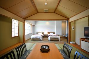 a room with two beds and a table and chairs at Awara Kitagata Onsen Kohanso Hana Yurari in Awara