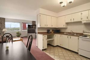 a kitchen with white cabinets and a table in a room at DC Lodge in Dawson Creek