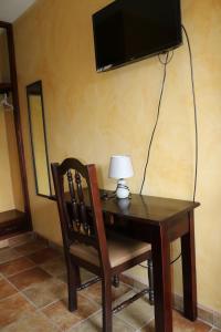 a desk with a chair and a television on a wall at Posada Gema de Copan in Santa Rosa de Copán