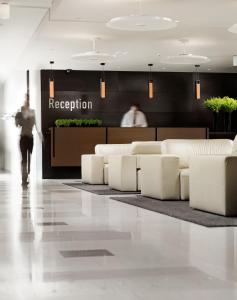 a person walking through a lobby with white furniture at Elefsina Hotel in Elefsina