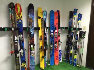 Un montón de tablas de snowboard están alineadas contra una pared. en Alp Bach Madarao en Iiyama