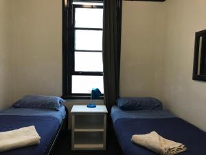 雪梨的住宿－庫吉海灘之家旅舍，带窗户的客房内的两张床