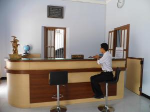 a man sitting at a bar in a room at Hotel Ilhami Blitar in Blitar
