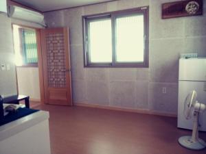 een lege kamer met een koelkast en een raam bij Mirinae Hanok Tradiational House in Gwangyang