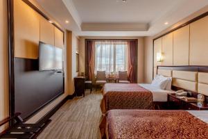a hotel room with two beds and a flat screen tv at Grand Hill Hotel Ulaanbaatar in Ulaanbaatar