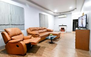 a living room with brown leather furniture and a tv at Relax @ Khao Yai in Ban Khanong Phra Klang (1)