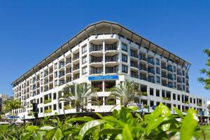 un gran edificio blanco con palmeras delante en Mantra Esplanade, en Cairns