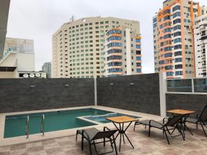 un patio en la azotea con piscina, mesas y edificios en Torre Marbella apartamentos de 2 y 3 dormitorios, en Salinas