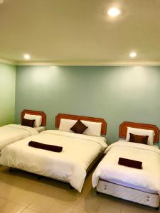 three beds in a room with a green wall at Hotel Seri Kangsar KK Hotel in Kuala Kangsar