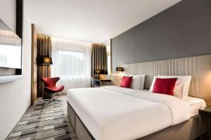 een hotelkamer met een groot wit bed en rode kussens bij Hotel International Brno in Brno