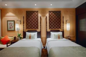 um quarto com duas camas e um sofá em Little Riverside Hoi An . A Luxury Hotel & Spa em Hoi An