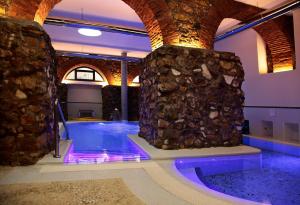 a swimming pool with a stone wall and purple lights at Hotel La Margherita & SPA in Alghero