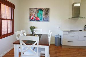 una cucina con tavolo, sedie bianche e un dipinto di Jodi's Beach Retreat Eden a Eden