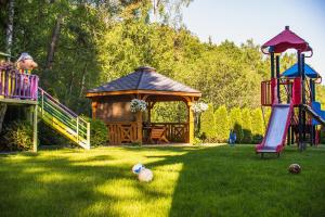 Ein Mann in einem Garten mit Spielplatz und Pavillon in der Unterkunft Apartamenty Aparton in Ustka