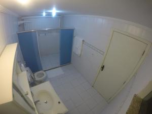 baño con aseo y puerta azul en Flat Arraial, en Arraial do Cabo