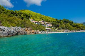 a beach with houses on a hill next to the water at Adrina Beach Hotel in Panormos Skopelos