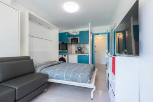 - une chambre avec des murs bleus, un lit et un canapé dans l'établissement Beautiful studio near sea (free parking), à Roquebrune-Cap-Martin