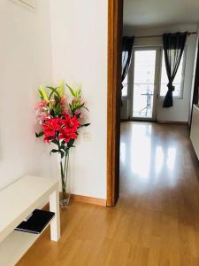 eine Vase roter Blumen auf einem Holzboden in der Unterkunft Apartment Melody in Ivanić-Grad