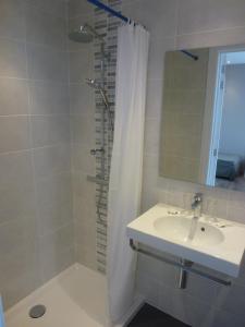 a bathroom with a shower and a sink and a mirror at Hotel Sabot D'Or in Blankenberge