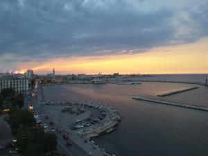 a city with cars parked next to the water at sunset at JR Hotels Bari Grande Albergo delle Nazioni in Bari