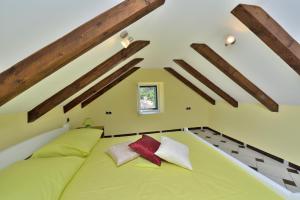 - duże zielone łóżko w pokoju z drewnianymi belkami stropowymi w obiekcie Apartments Carpe Diem w mieście Novigrad