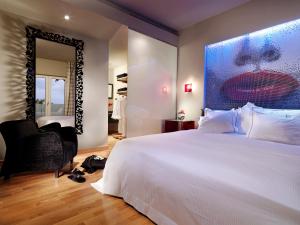 a bedroom with a white bed and a painting of a woman at Out Of The Blue Resort & Spa in Agia Pelagia
