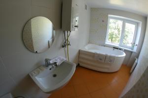 y baño con lavabo, bañera y espejo. en Tvirtovė, en Vilna