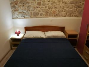 1 dormitorio con 1 cama con pared de piedra en Apartment Ana 2 en Sveti Filip i Jakov