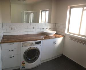 a bathroom with a sink and a washing machine at 3ree- Spacious & Charming Apartment in Devonport